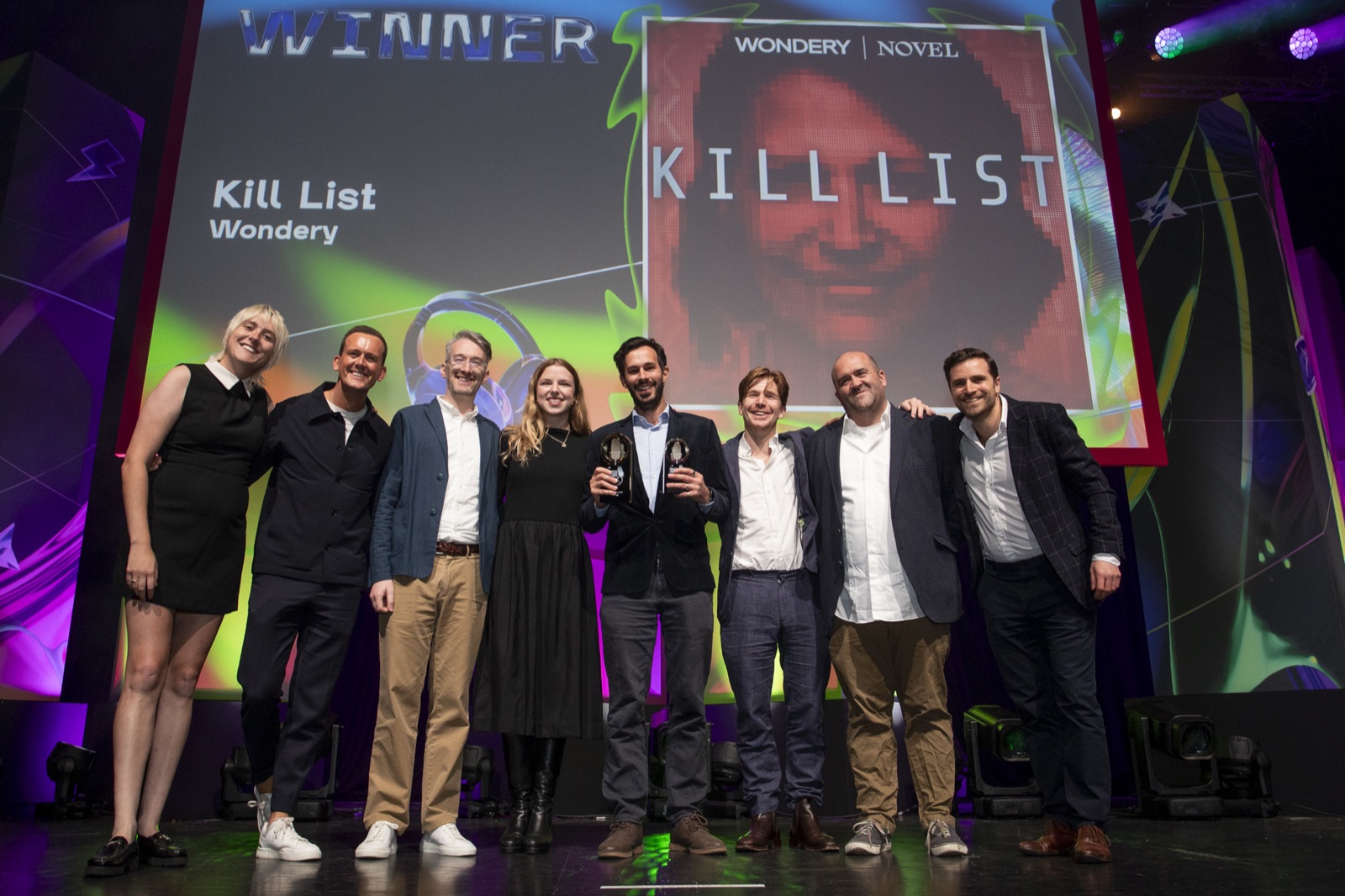 The Kill List team on stage winning at the British Podcast Awards, with Carl Miller holding the trophies